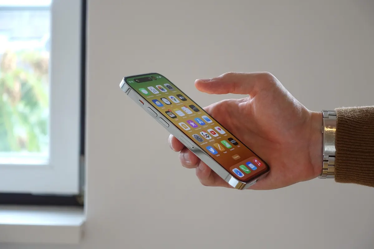 Swift for iOS Development Hand holding an iPhone displaying app icons for Swift iOS development