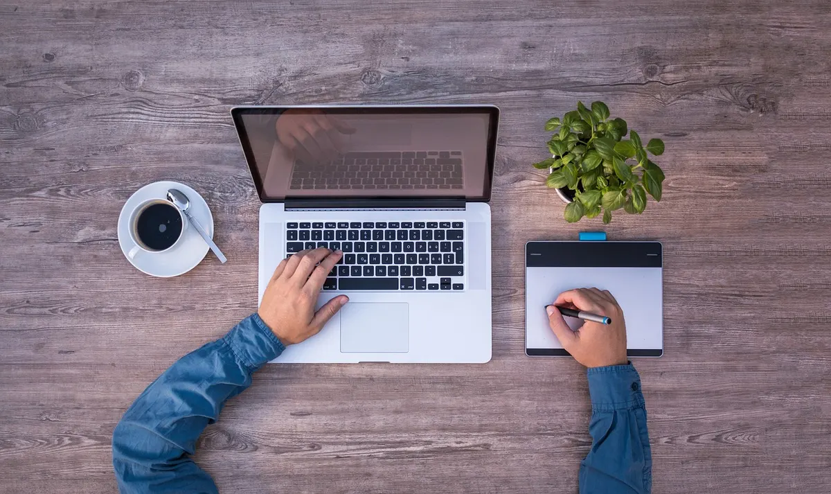 Web Design Web designer working on a laptop and graphics tablet at a creative studio desk